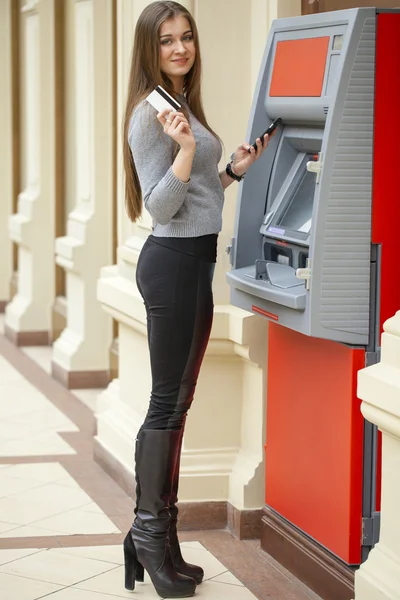 Mujer rubia en un abrigo rojo con un teléfono en la mano en la espalda — Foto de Stock