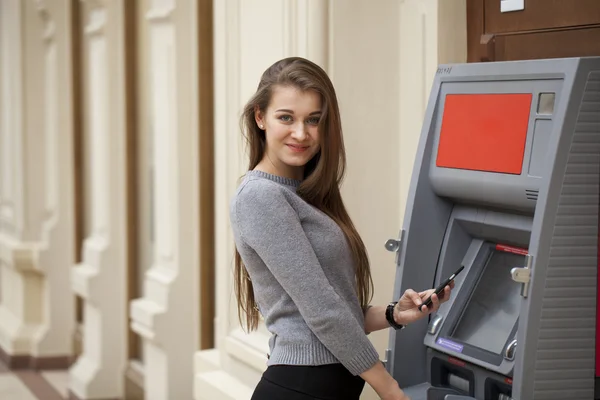 Jovem mulher morena feliz retirando dinheiro do cartão de crédito em — Fotografia de Stock