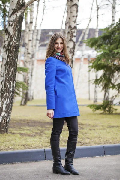 Young beautiful woman in blue coat on the background of spring s — Stock Photo, Image
