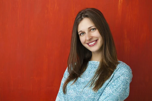 Portrait of a beautiful young woman in a turquoise dress on red — Stock Photo, Image