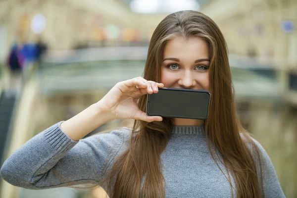 Young woman covers her face screen smartphone — Stock Photo, Image