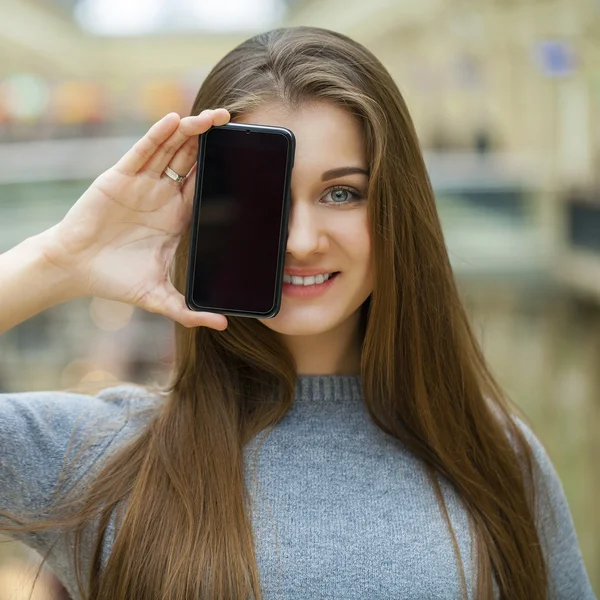 若い女性は彼女の顔のスクリーンのスマート フォンをカバーします。 — ストック写真