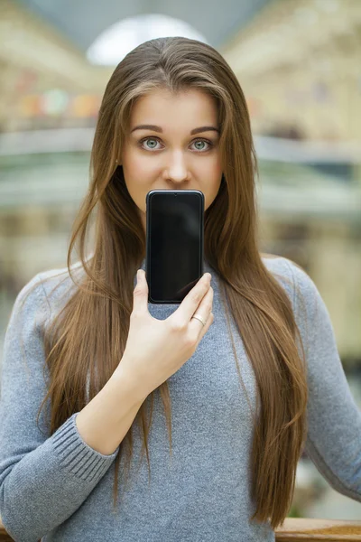 若い女性は彼女の顔のスクリーンのスマート フォンをカバーします。 — ストック写真