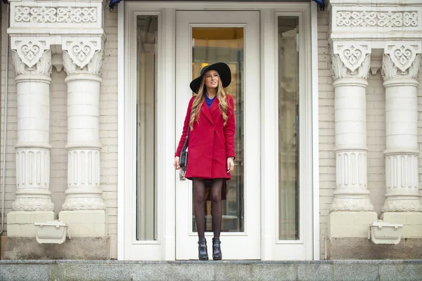 Giovane donna bionda felice in cappotto rosso cammina sulla strada primaverile — Foto Stock