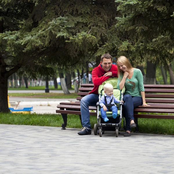 Jonge ouders zitten op een bankje met zijn jonge zoon — Stockfoto