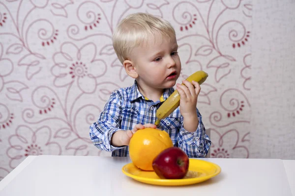 Beautiful little baby boy eats banana — Stock Photo, Image