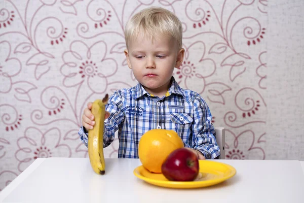 Beautiful little baby boy eats banana — Stock Photo, Image