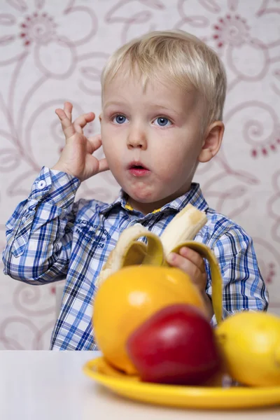 Beautiful little baby boy eats banana — Stock Photo, Image