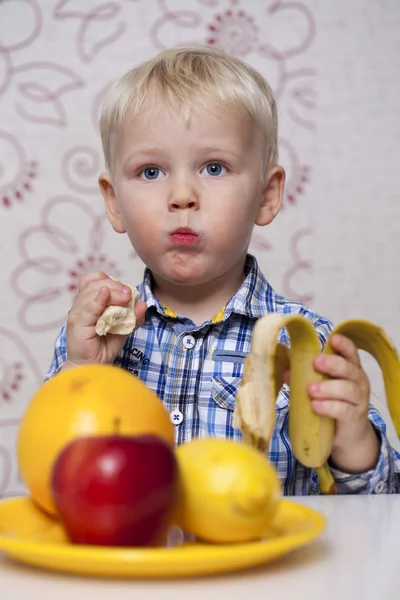 Beautiful little baby boy eats banana — Stock Photo, Image