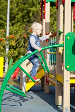 Küçük çocuk oyun alanında oynuyor.
