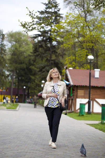 Äldre kvinna promenader i vår park — Stockfoto