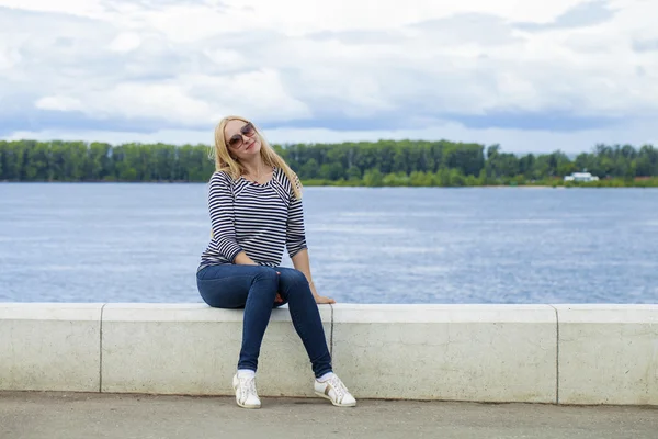 Młoda kobieta piękne niebieskie dżinsy siedzi w lato ulicy par — Zdjęcie stockowe