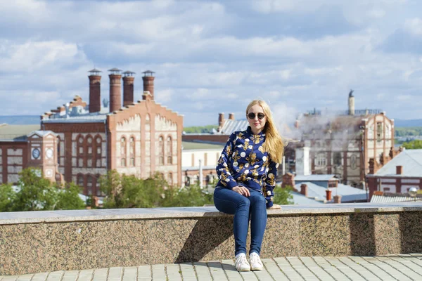 Young beautiful woman in blue jeans sitting in summer street par — Stock Photo, Image