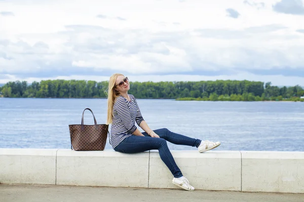 Jovem mulher bonita em jeans azul sentado na rua de verão par — Fotografia de Stock