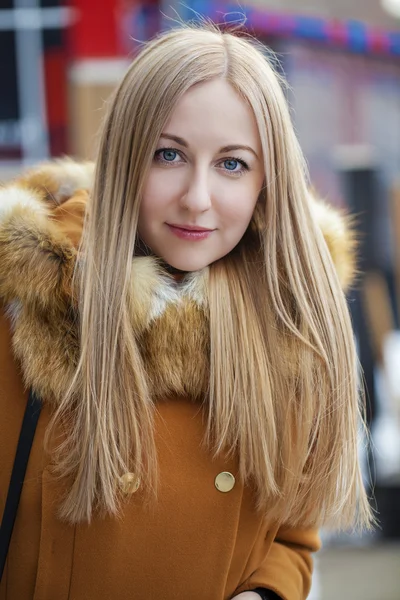 Mujer rubia joven feliz en el fondo de una calle de invierno —  Fotos de Stock