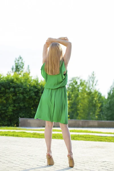 Jeune belle femme en robe verte posant en plein air sous le soleil nous — Photo