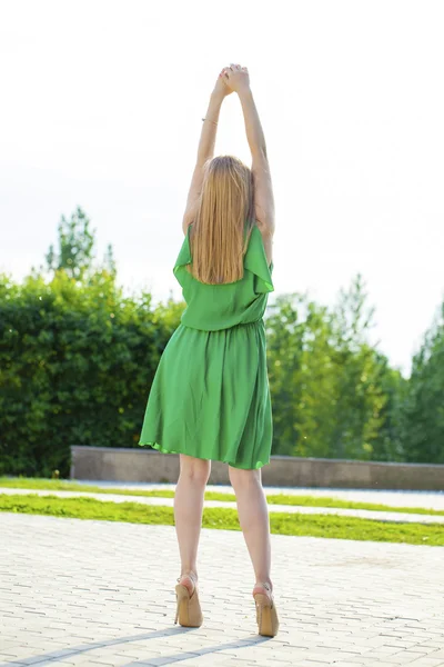 Jeune belle femme en robe verte posant en plein air sous le soleil nous — Photo