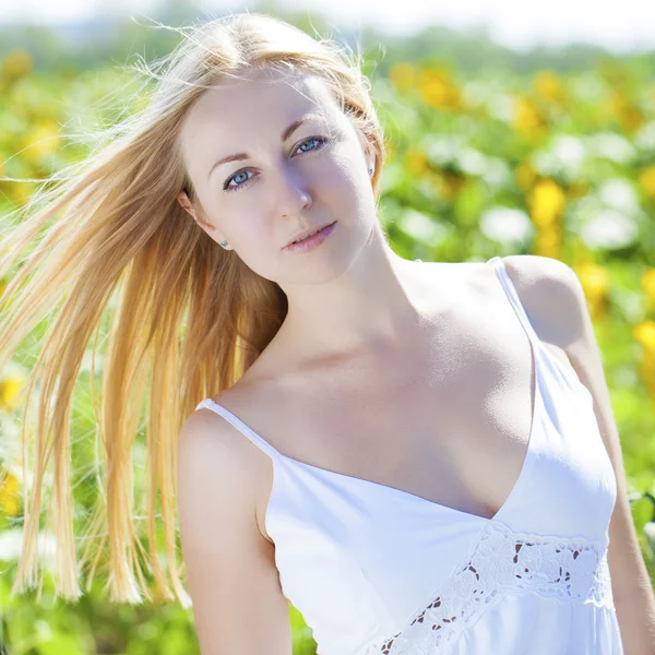 Porträtt av en vacker ung blond kvinna i en vit klänning på en — Stockfoto