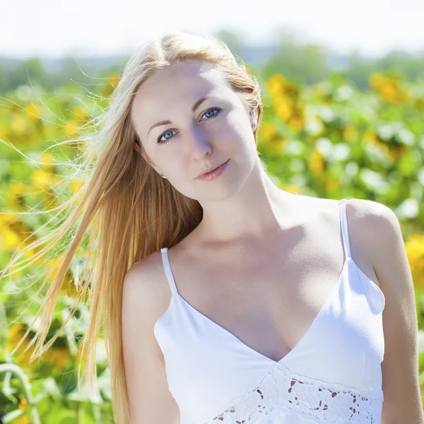Portret van een mooie jonge blonde vrouw in een witte jurk op een — Stockfoto