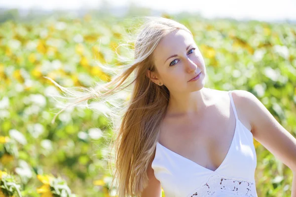 Porträt einer schönen jungen blonden Frau in einem weißen Kleid auf einem — Stockfoto