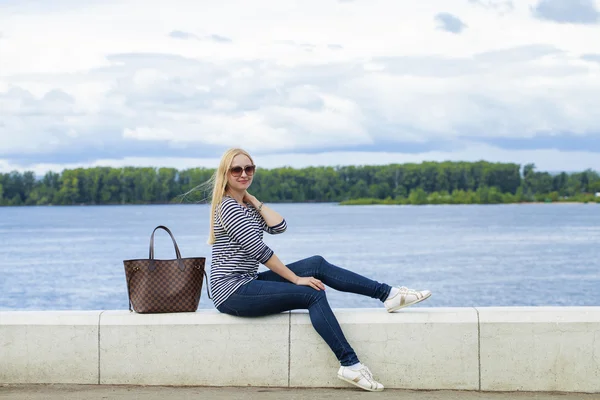 Giovane bella donna in jeans blu seduta in strada estiva par — Foto Stock