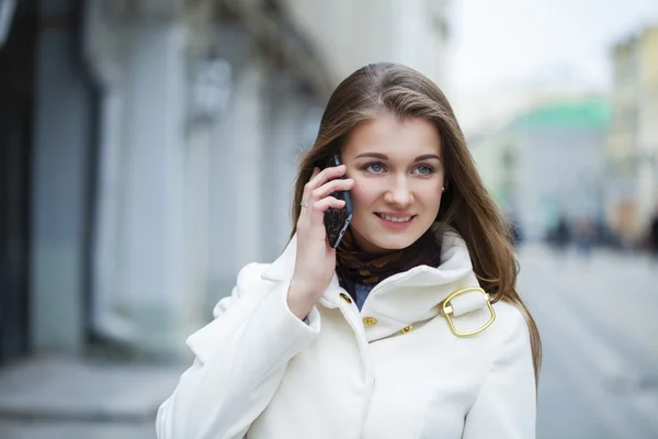 Portrait de jeune fille brune heureuse en manteau blanc parlant sur t — Photo