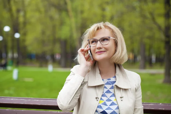 Mature beautiful blonde woman is calling on a cell phone — Stock Photo, Image