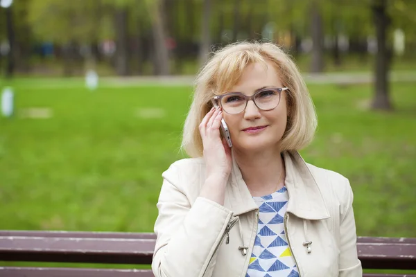 Mature beautiful blonde woman is calling on a cell phone — Stock Photo, Image