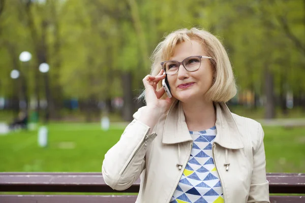 Mature beautiful blonde woman is calling on a cell phone — Stock Photo, Image