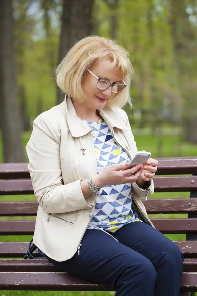 Mooie rijpe vrouw leest het bericht op de telefoon — Stockfoto