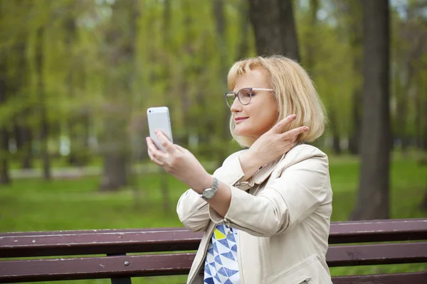 Reife schöne Frau liest die Nachricht am Telefon — Stockfoto