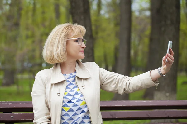 Mature beautiful blonde woman is calling on a cell phone — Stock Photo, Image