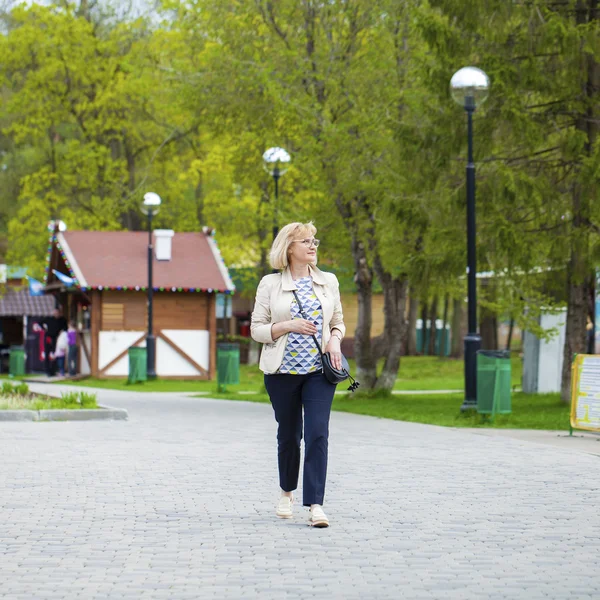 Äldre kvinna promenader i vår park — Stockfoto