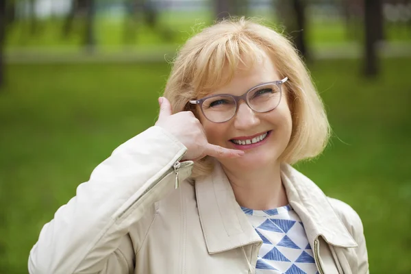 Happy smiling old blonde woman with call me gesture — Stock Photo, Image