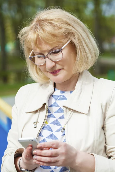 Äldre vacker kvinna läser meddelandet på telefonen — Stockfoto