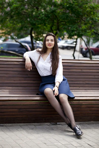 Young beautiful girl sitting on a bench in the summer park — Stock Photo, Image