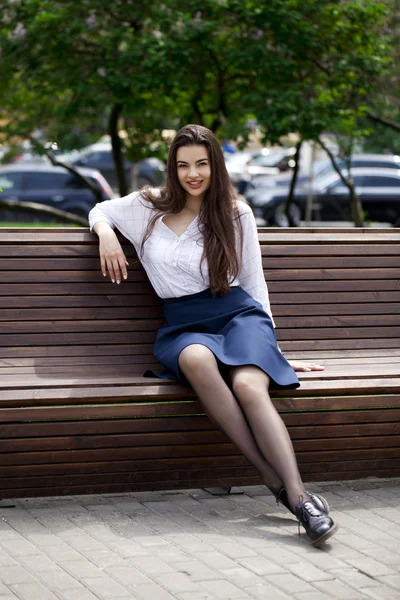 Mooi meisje zittend op een bankje in het park van de zomer — Stockfoto