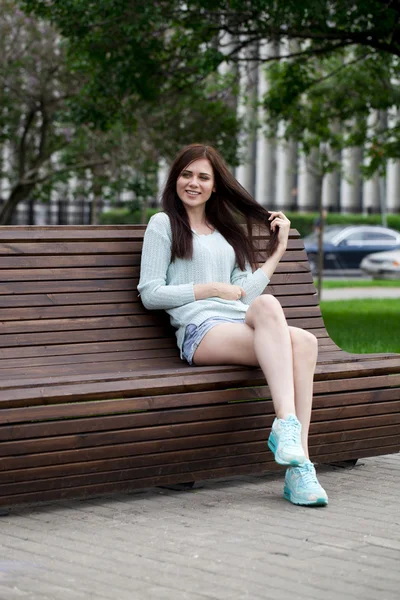 Młoda piękna dziewczyna siedzi na ławce w parku lato — Zdjęcie stockowe