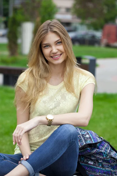 Jeune belle fille assise sur un banc dans le parc d'été — Photo