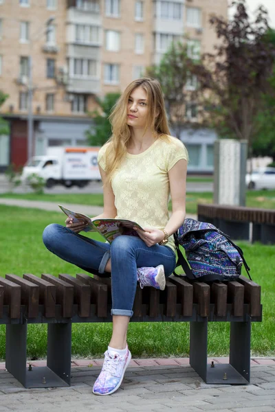 Mooi meisje zittend op een bankje in het park van de zomer — Stockfoto