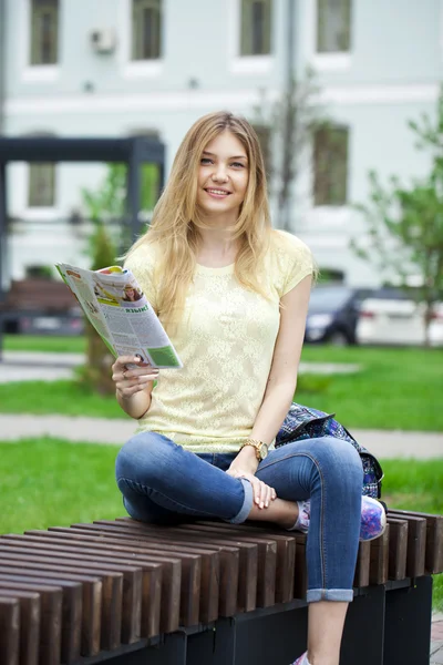 Junges schönes Mädchen sitzt auf einer Bank im Sommerpark — Stockfoto