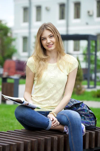 Junges schönes Mädchen sitzt auf einer Bank im Sommerpark — Stockfoto