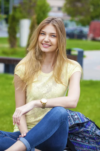 Jovem menina bonita sentada em um banco no parque de verão — Fotografia de Stock