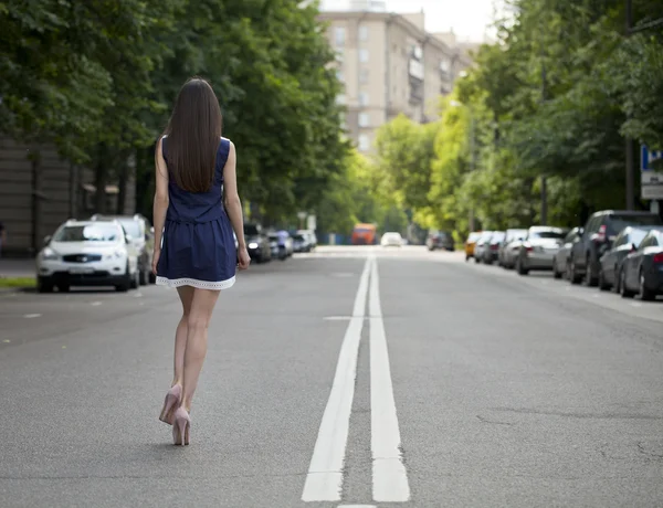 Young beautiful woman in a blue short dress walking on the road — Stock Photo, Image