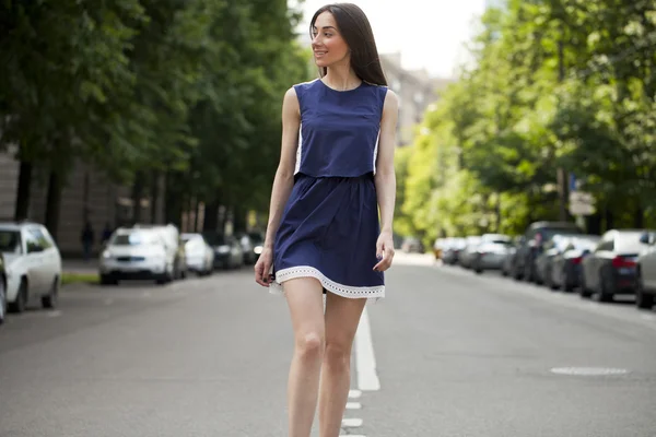 Jovem mulher bonita em um vestido curto azul andando na estrada — Fotografia de Stock