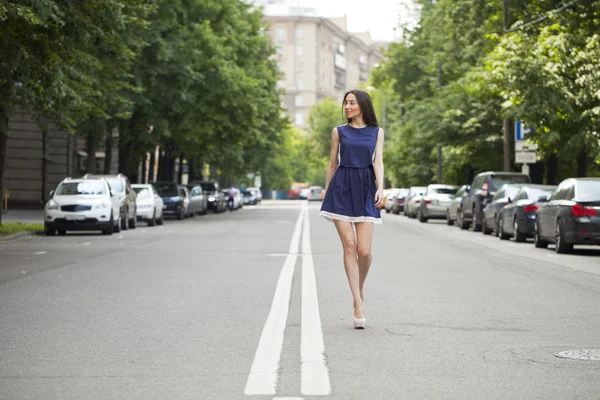 Młoda piękna kobieta w niebieską sukienkę krótkiego spaceru na drodze — Zdjęcie stockowe