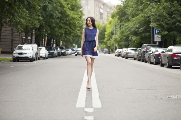 Jeune belle femme dans une robe courte bleue marchant sur la route — Photo