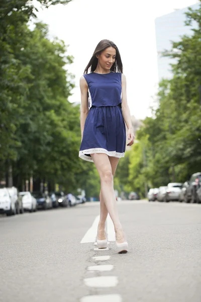 Joven hermosa mujer en un vestido corto azul caminando por el camino —  Fotos de Stock