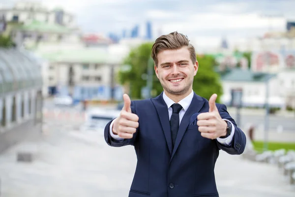 Businessman showing ok sign in front of an office building — Stock Photo, Image