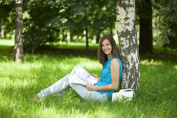 Happy woman leafing through a magazine while sitting in the summ — Stock Photo, Image